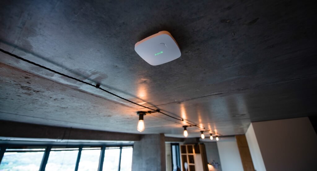 Sensor asap pintar AJAX FireProtect terpasang di langit-langit ruang modern, sebagai bagian dari sistem proteksi kebakaran dari distributor resmi AJAX, PT. LAX Teknologi Indonesia.